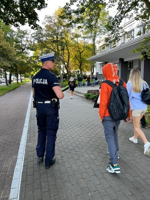 Zdjęcie przedstawiające policjanta, który rozmawia z młodzieżą na temat bezpieczeństwa w ruchu drogowym