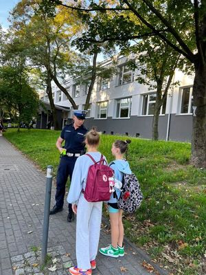 Zdjęcie przedstawiające policjanta, który rozmawia z dziećmi na temat bezpieczeństwa w ruchu drogowym