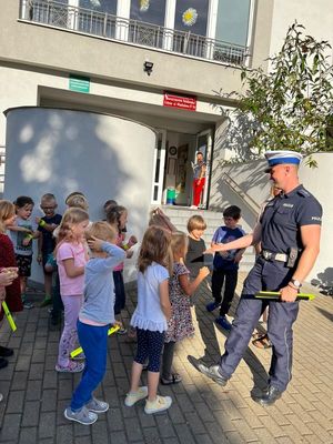 Zdjęcie przedstawiające policjanta, który rozmawia z dziećmi na temat bezpieczeństwa w ruchu drogowym