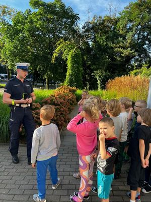 Zdjęcie przedstawiające policjanta, który rozmawia z dziećmi na temat bezpieczeństwa w ruchu drogowym