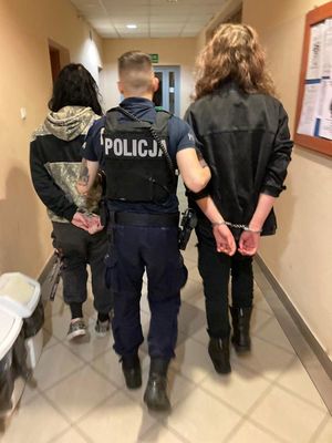 Zdjęcie przedstawiające policjanta prowadzącego zatrzymane osoby