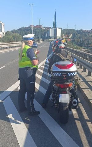 Zdjęcie przedstawiające policjantkę, która przeprowadza kontrolę motocyklisty