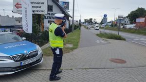 Zdjęcie przedstawiające policjanta podczas wykonywania pomiaru prędkości