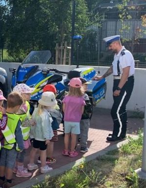 Zdjęcie przedstawiające policjanta drogówki, który prezentuje dzieciom motocykl policyjny