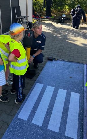 Zdjęcie przedstawiające policjantkę drogówki, która tłumaczy dziecku zasady bezpieczeństwa na drodze