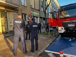 Zdjęcie przedstawiające wóz strażacki oraz policjantów, którzy zabezpieczają miejsce zdarzenia.