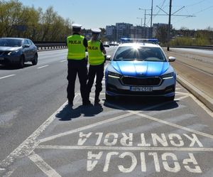 Zdjęcie przedstawiające policjantów na tle radiowozu