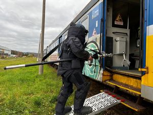 Zdjęcie przedstawiające policjanta z przeszkoleniem minersko-pirotechnicznym wchodzącego do pociągu