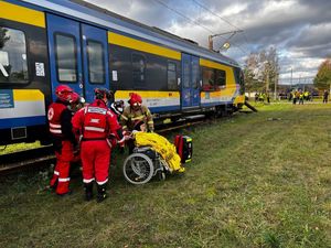 Zdjęcie przedstawiające służby podczas udzielania pomocy osobie na wózku inwalidzkim