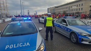 Zdjęcie przedstawiające stojącego tyłem policjanta między dwoma oznakowanymi radiowozami. W tle widać osoby w strojach Mikołajów