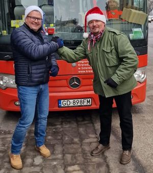 Zdjęcie przedstawiające dwóch mężczyzn przed czerwonym ambulansem do poboru krwi