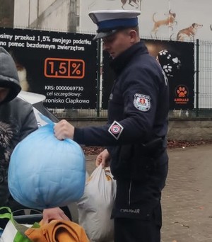 Zdjęcie przedstawiające policjanta z darami dla bezdomnych zwierząt