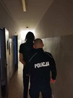 Zdjęcie przedstawiające policjanta, który prowadzi zatrzymanego mężczyznę