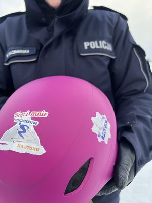 Zdjęcie przedstawiające policjantkę, która trzyma kask z logo Policji i naklejką z napisem Kręci mnie bezpieczeństwo na stoku