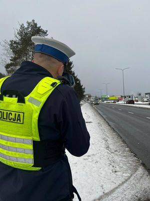 Zdjęcie przedstawiające policjanta, podczas pomiaru prędkości