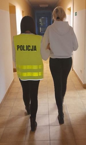 Zdjęcie przedstawiające policjantkę, która prowadzi zatrzymaną kobietę