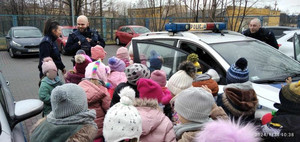 Zdjęcie przedstawiające policjantów i dzieci na tle radiowozu