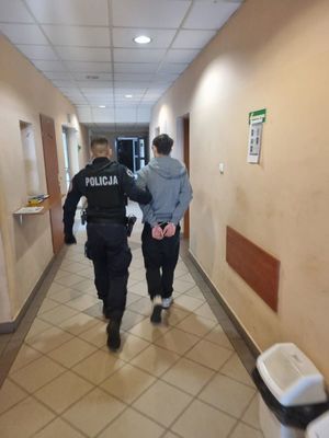 Zdjęcie przedstawiające policjanta, który prowadzi zatrzymanego mężczyznę