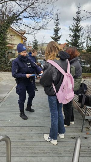 Zdjęcie przedstawiające policjantkę, która rozdaje młodzieży ulotki