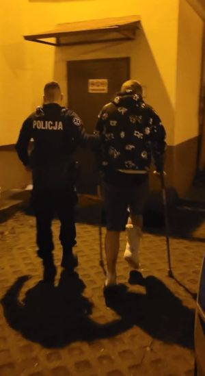 Zdjęcie przedstawiające policjanta, prowadzącego zatrzymanego mężczyznę