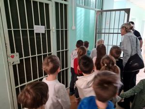 Zdjęcie przedstawiające przedszkolaki wraz z opiekunką podczas oglądania policyjnej celi