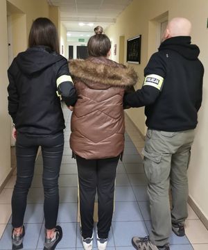 Zdjęcie przedstawiające policjantkę i policjanta, którzy prowadzą zatrzymaną kobietę