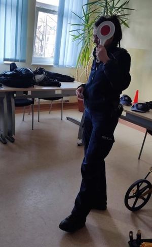 Zdjęcie przedstawiające policjantkę, która stoi i ma w ręku tarczę drogową