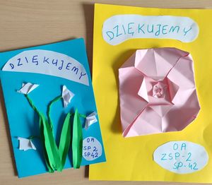 Zdjęcie przedstawiające dwie prace wykonane przez dzieci, które zostały przekazane policjantom w podziękowaniu za spotkanie. Na pracy wykonane są kwiaty.