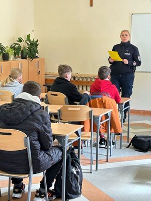 Zdjęcie przedstawiające policjantkę oraz siedzących w ławkach uczniów.