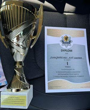 Zdjęcie przedstawiające puchar i dyplom dla policjantów z Gdyni, którzy zajęli pierwsze miejsce w wojewódzkim etapie zawodów na najlepszego ratownika z kwalifikowanej pierwszej pomocy.