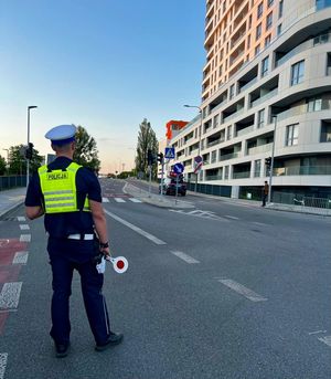 Zdjęcie przedstawiające policjanta ruchu drogowego, który zabezpiecza drogę przed półmaratonem