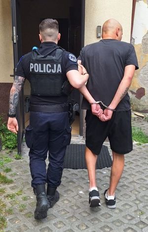 Zdjęcie przedstawiające policjanta, który prowadzi zatrzymanego mężczyznę.