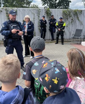 Zdjęcie przedstawiające policjantkę oraz czterech policjantów, którzy na placu rozmawiają z dziećmi