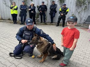 Zdjęcie przedstawiające dwie policjantki i pięciu policjantów. Jeden z policjantów kuca przy psie służbowym, przy którym stoi chłopiec.