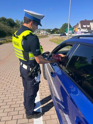 Zdjęcie przedstawiające policjanta, wręczającego kierowcy apteczkę samochodową