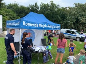 Zdjęcie przedstawiające uczestników Pikniku Zdrowia oraz policjantów, którzy przyglądają się pokazowi umiejętności psa służbowego.