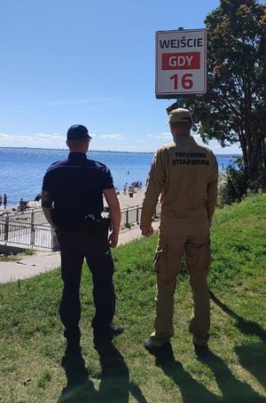 Zdjęcie przedstawiające wspólny patrol Policji i PSP na plaży.