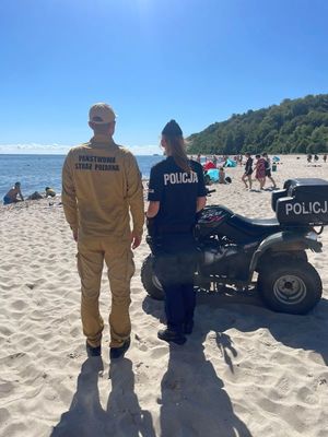 Zdjęcie przedstawiające wspólny patrol Policji i PSP na plaży.