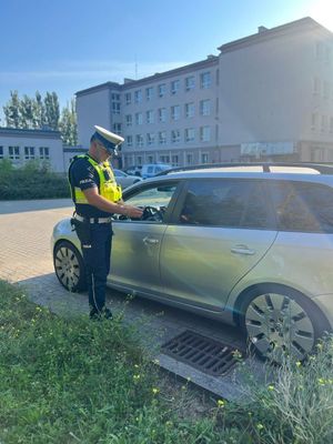 Zdjęcie przedstawiające policjanta podczas legitymowania kierowcy.