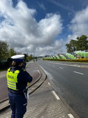 Zdjęcie przedstawiające policjantkę podczas wykonywania pomiaru prędkości.