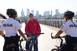 Zdjęcie przedstawiające dwie policjantki na rowerach oraz młodego mężczyznę, również na rowerze.