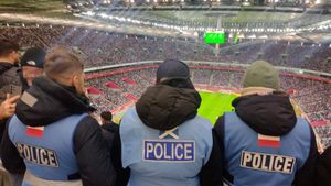 Zdjęcie przedstawiające stojących tyłem trzech policjantów spottersów na stadionie narodowym w Warszawie