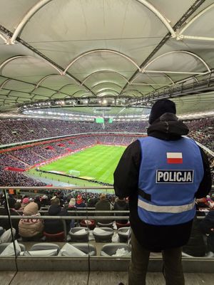 Zdjęcie przedstawiające stojącego tyłem policjanta spottersa  na stadionie narodowym w Warszawie