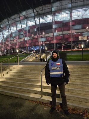 Zdjęcie przedstawiające policjanta spottersa  przed stadionem narodowym w Warszawie