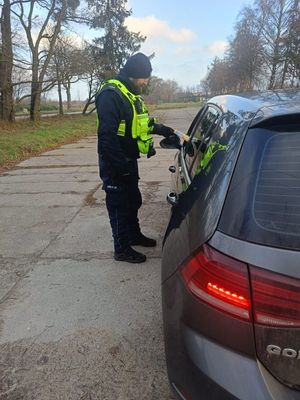 Zdjęcie przedstawiające policjanta, który wręcza kierowcy latarkę samochodową.