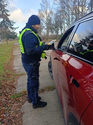 Zdjęcie przedstawiające policjanta, który wręcza kierowcy latarkę samochodową.