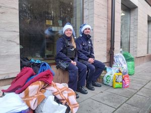 Zdjęcie przedstawiające dwóch policjantów w mikołajkowych czapkach koloru niebieskiego