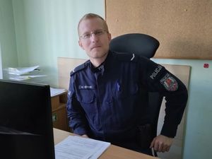 Zdjęcie przedstawiające policjanta siedzącego przy biurku.