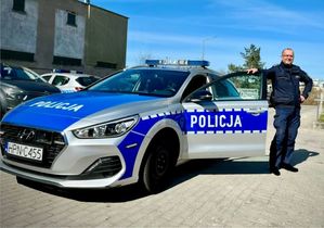 Zdjęcie przedstawiające policjanta, stojącego przy radiowozie.