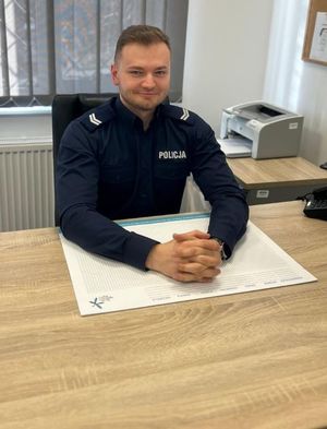 Zdjęcie przedstawiające policjanta przy biurku.